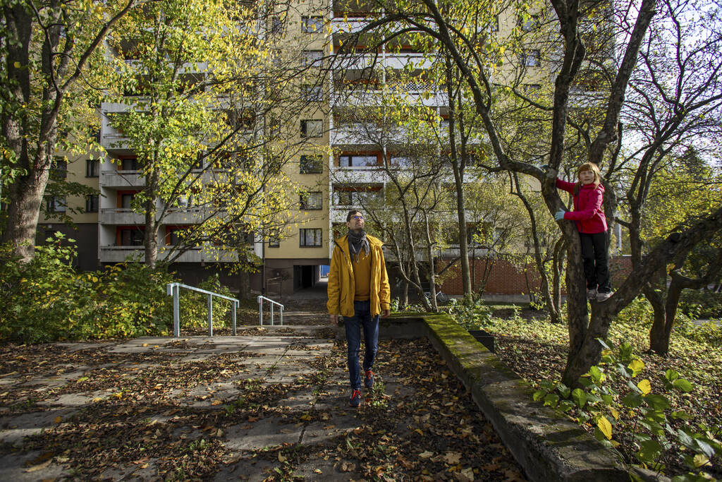 Lapsi on kiivennyt puuhun kerrostalon edessä aurinkoisena syyspäivänä